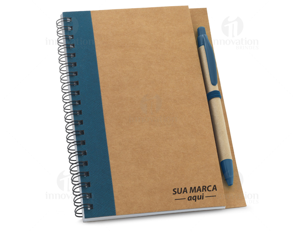Caderno B6 espiral de capa dura em cartão, com 120 páginas lisas em papel reciclado e suporte para esferográfica (inclusa). 