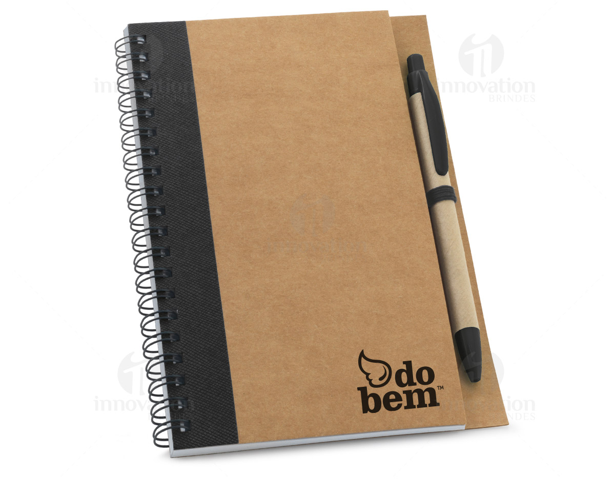 Caderno B6 espiral de capa dura em cartão, com 120 páginas lisas em papel reciclado e suporte para esferográfica (inclusa). 