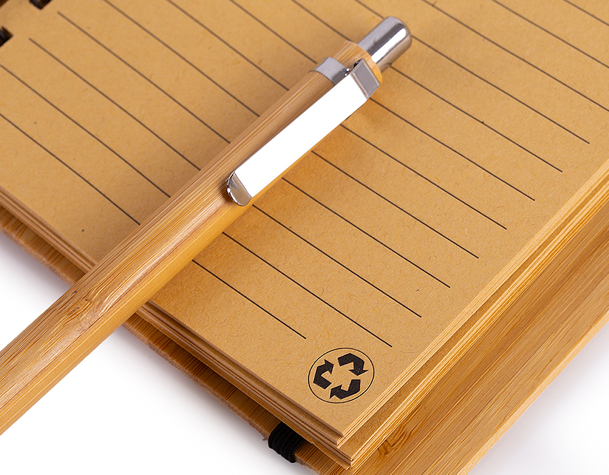 1 Bloco de anotações 18x13,5cm capa de bambu, com elástico, suporte para canetas e miolo com 70 folhas pautadas na cor bege;
1 Caneta de bambu com partes em metal.