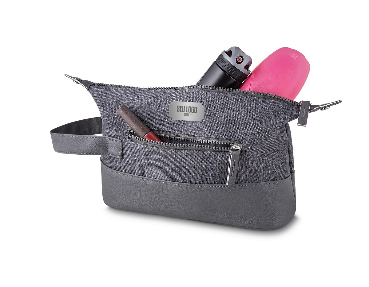 Necessaire de nylon com detalhes em couro sintético. Possui alça lateral, pequenas abas nas laterais com botões para ajuste, compartimento principal superior e um pequeno compartimento frontal, zíperes acompanham puxador em couro sintético.
