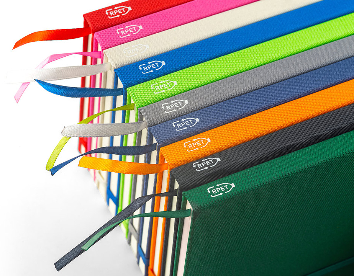 Caderno A5 de capa dura em poliéster 100% reciclado (100% rPET) 300D, com cantos redondos. Contém 80 folhas pautadas em papel cor de marfim reciclado, fita separadora, suporte para esferográfica (não inclusa) e elástico para fecho do caderno. Na parte inferior da lombada, tem impresso em branco o símbolo do rPET. 143 x 211 mm