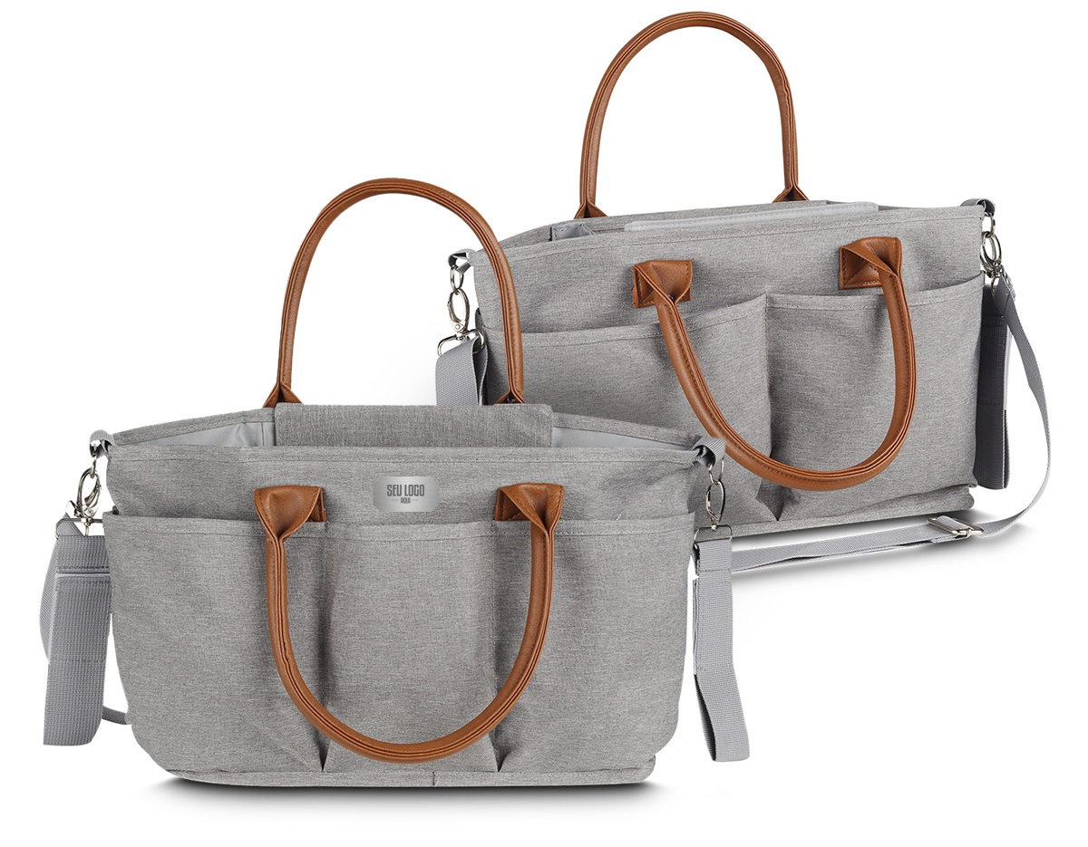 Nossa bolsa multifuncional de 8 litros é projetada para se adaptar a diferentes ocasiões. Produzida em poliéster com tecido resistente à água, possui alças em couro sintético que combinam com um design moderno e prático, ideal para guardar diversos itens, como os de bebê, trabalho e afins. A parte interna oferece um espaço amplo e adaptável, com duas divisórias contendo velcro que permitem criar até três compartimentos separados. Além disso, possui um bolso com zíper e três bolsos internos, sendo um deles com elástico para facilitar o acesso. O fechamento da bolsa é feito por um compartimento que protege a parte central. Para torná-la ainda mais funcional, conta com um compartimento térmico integrado, ajudando a manter a bebida na temperatura ideal por mais tempo. Na parte externa, há cinco bolsos adicionais, além de um engate de nylon com fechamento em velcro, perfeito para prender em carrinhos de bebê ou onde desejar. Suas alças podem ser usadas no ombro ou nas mãos. Além disso, conta com uma alça extra ajustável e removível, oferecendo mais versatilidade sempre que necessário. Essa bolsa é uma excelente opção de brinde, unindo modernidade e praticidade.