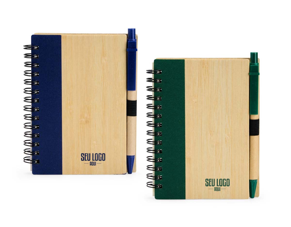 Caderno com capa de casca de bambu e faixa colorida, encadernação Wire-O e cerca de 70 folhas pautadas amareladas. Acompanha caneta esferográfica azul (0,8 mm), com corpo de papelão, clip, ponteira plástica e acionamento por clique. Elástico na capa para fixar a caneta.