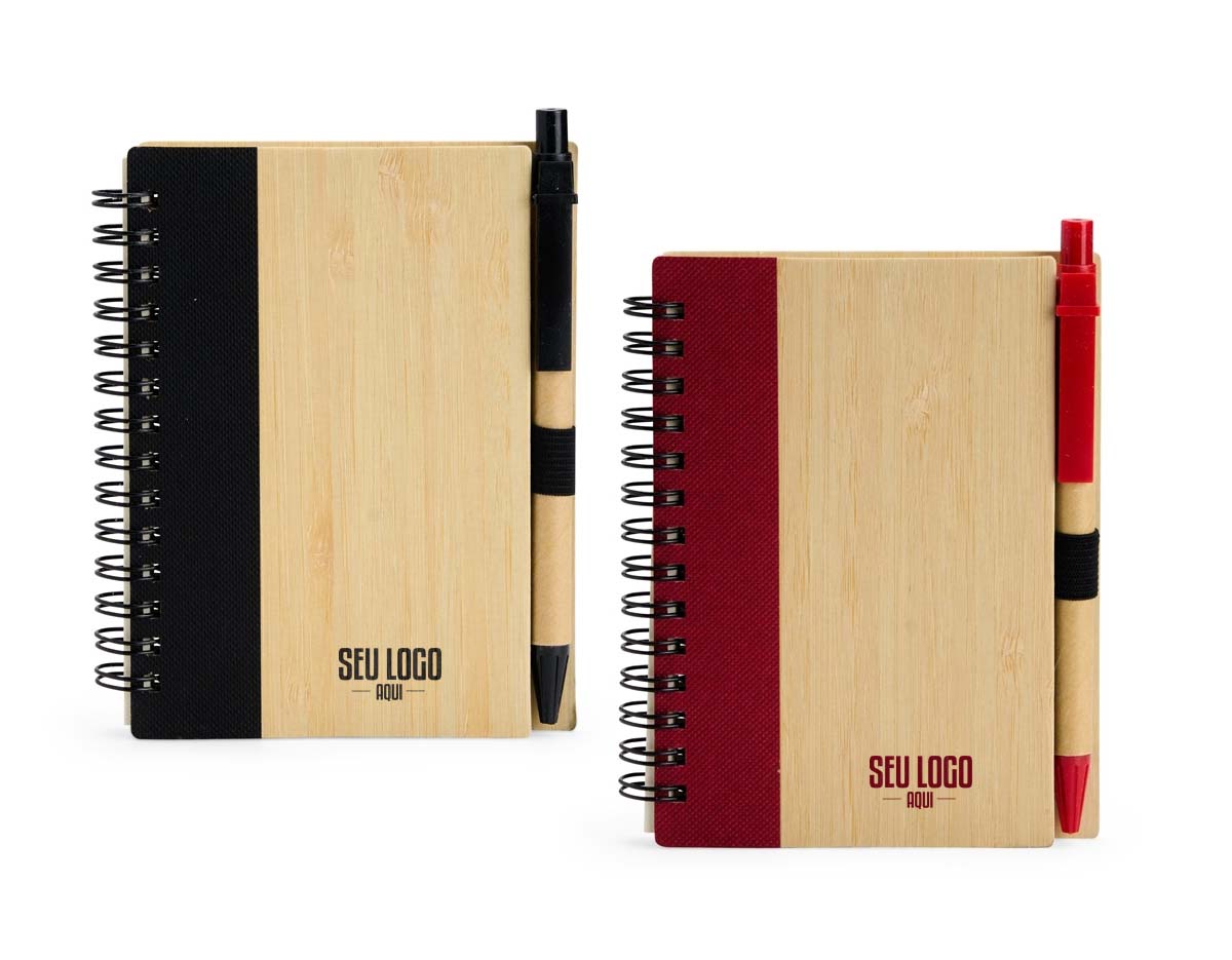 Caderno com capa de casca de bambu e faixa colorida, encadernação Wire-O e cerca de 70 folhas pautadas amareladas. Acompanha caneta esferográfica azul (0,8 mm), com corpo de papelão, clip, ponteira plástica e acionamento por clique. Elástico na capa para fixar a caneta.
