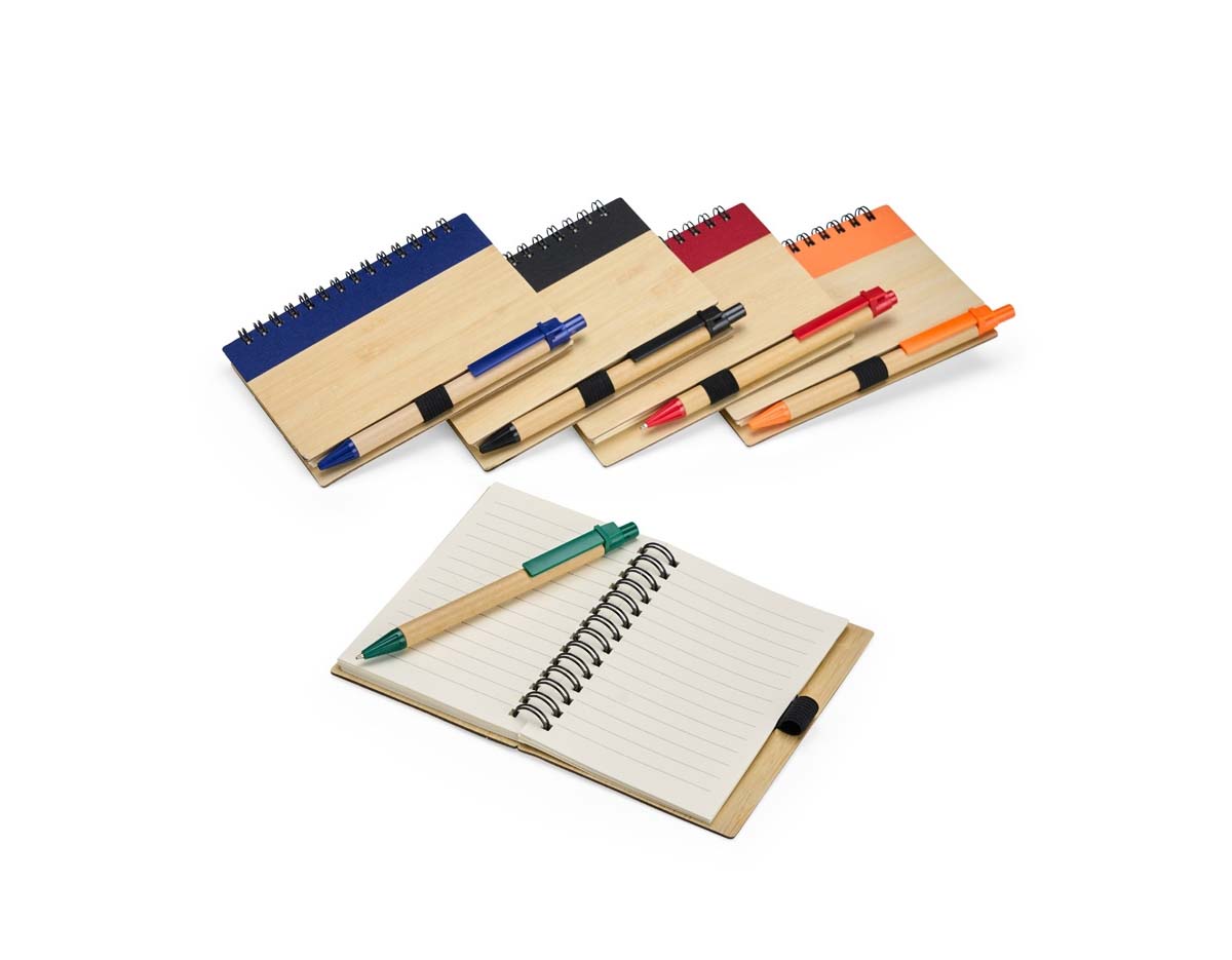 Caderno com capa de casca de bambu e faixa colorida, encadernação Wire-O e cerca de 70 folhas pautadas amareladas. Acompanha caneta esferográfica azul (0,8 mm), com corpo de papelão, clip, ponteira plástica e acionamento por clique. Elástico na capa para fixar a caneta.