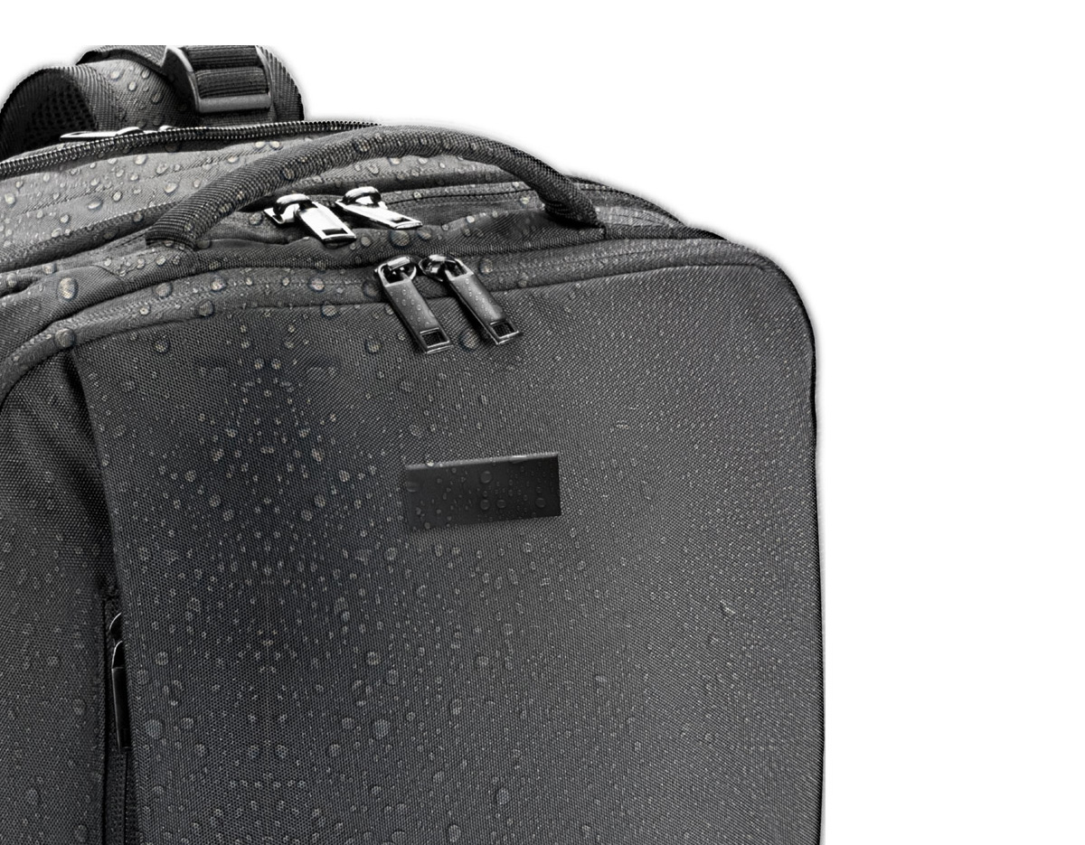 Mochila de viagem em poliéster reciclado 600D com acabamento repelente à água e forro em poliéster reciclado 210D. Possui três compartimentos principais: traseiro com bolsos para notebook até 17.3" e tablet até 10.1", central expansível para roupas e frontal com divisórias internas. Conta com três bolsos externos, dois com forro em PEVA, placa metálica removível, alças ajustáveis, cintas de compressão, pegas almofadadas e alça para trolley. Capacidade até 29 L.