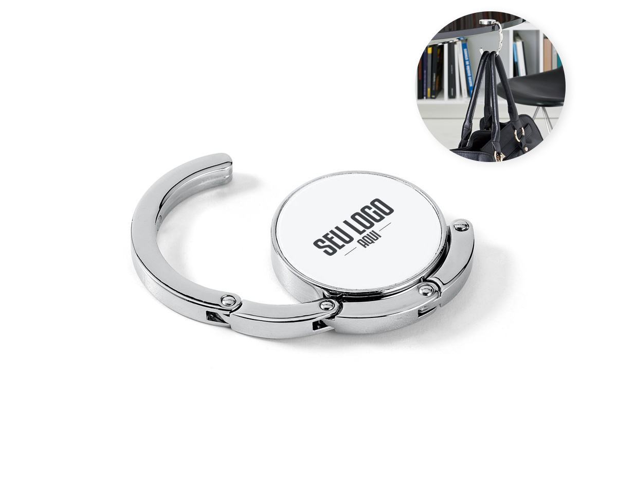 Suporte de bolsa em metal resistente, ideal para manter sua bolsa sempre por perto e longe do chão. Pode ser apoiado em superfícies como mesas para pendurar a alça com segurança. Quando não está em uso, recolhe-se de forma compacta e se mantém fixo à base por um ímã discreto e funcional.