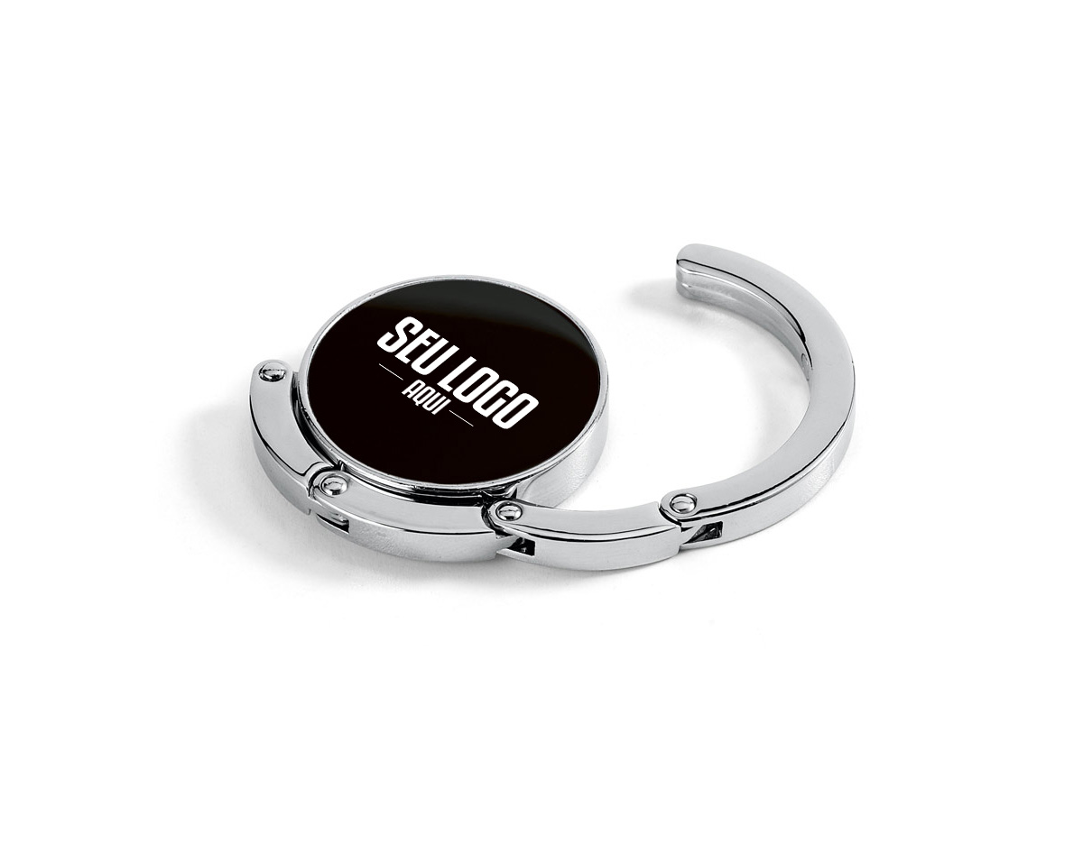 Suporte de bolsa em metal resistente, ideal para manter sua bolsa sempre por perto e longe do chão. Pode ser apoiado em superfícies como mesas para pendurar a alça com segurança. Quando não está em uso, recolhe-se de forma compacta e se mantém fixo à base por um ímã discreto e funcional.