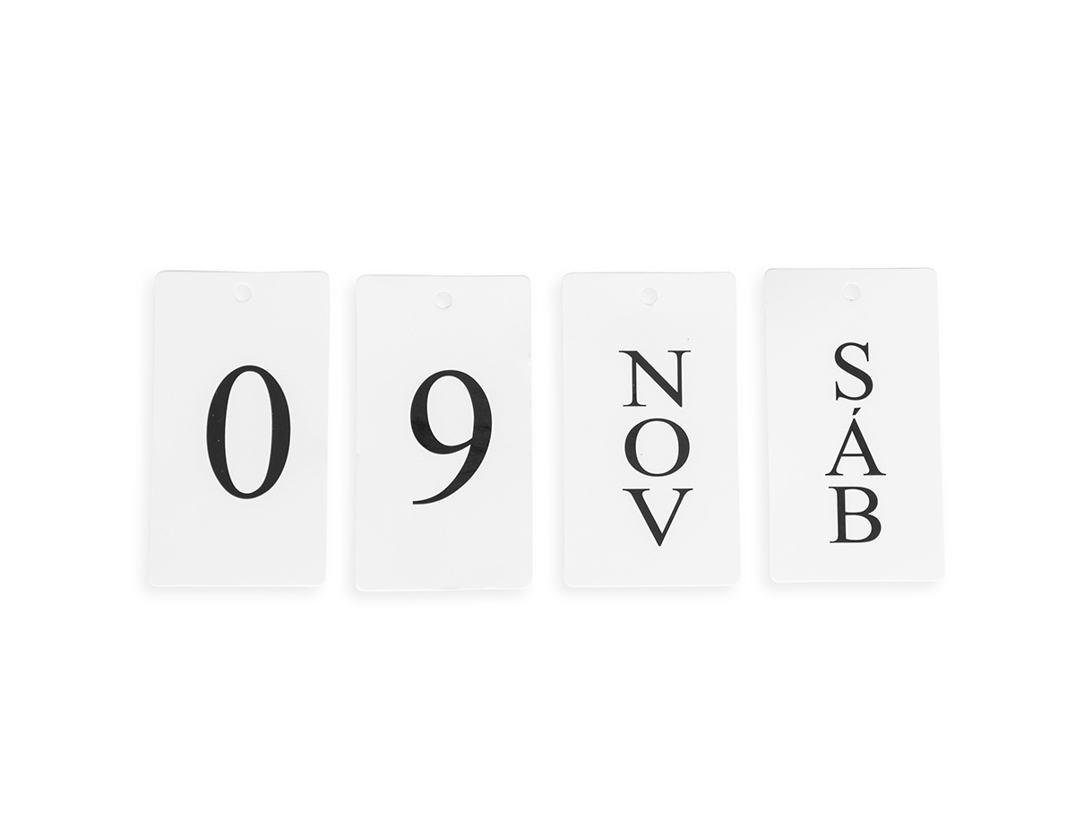 Calendário permanente de mesa com base feita em MDF e moldura de ferro. Conta com fichas em papel cartão que permitem montar a data, trazendo o dia em números e o mês e os dias da semana em versões abreviadas.